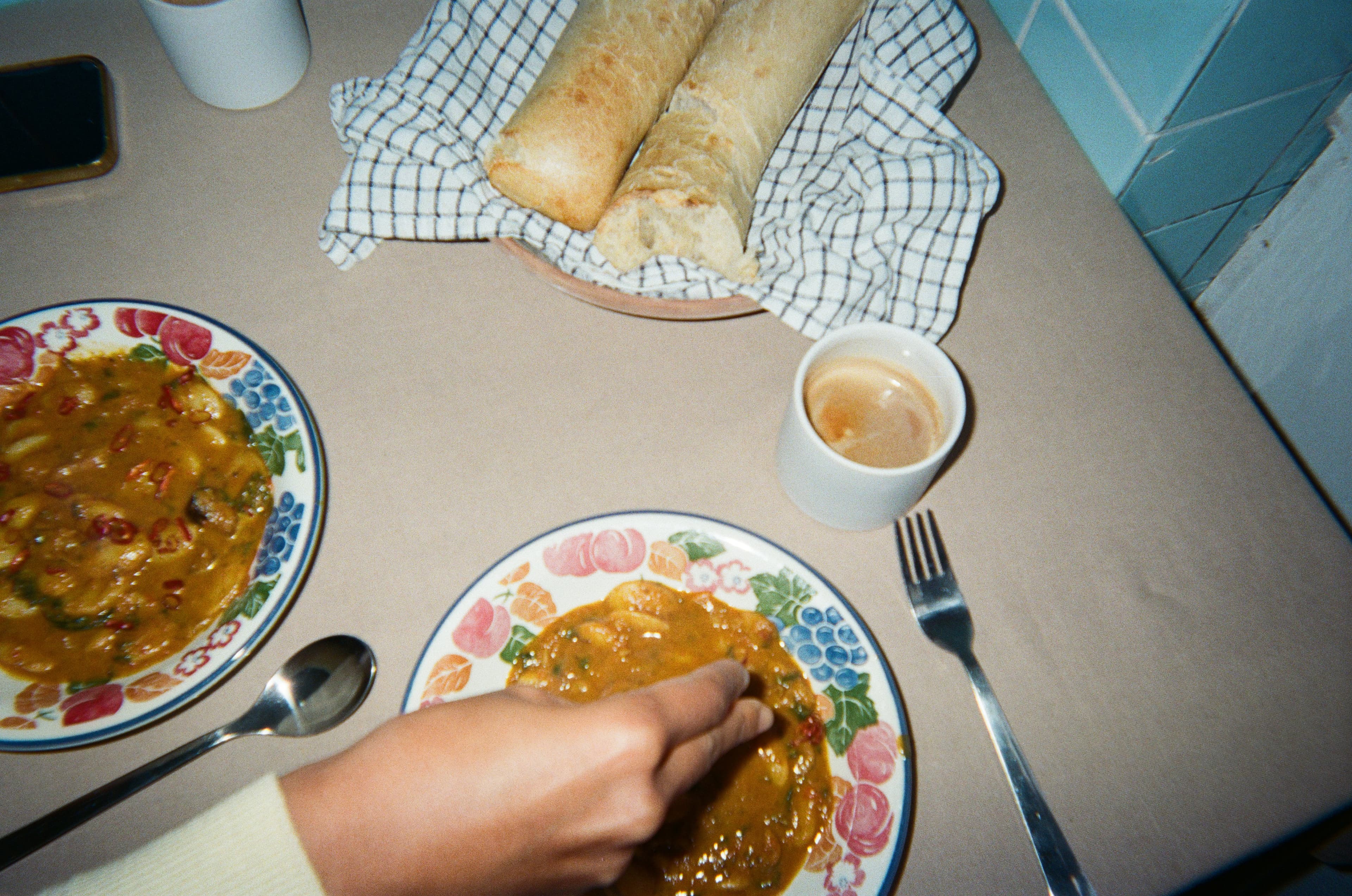 Chef plating a colorful curry bowl with fresh herbs
